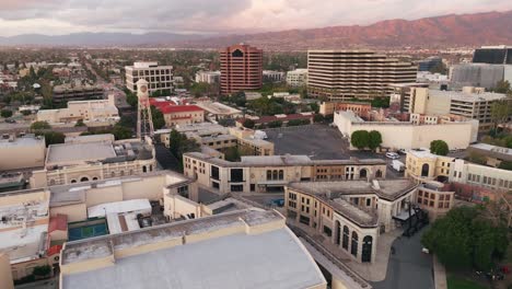 Flying-Over-Warner-Brothers-Studio-Back-Lot-with-Drone,-Aerial-Footage-of-New-York-Street-Set-WB-Water-Tower-and-other-Stages-Surrounded-by-Corporate-Buildings