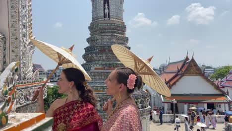 Dos-Chicas-Europeas-Vestidas-Como-Tailandesas-Sonriendo-En-El-Templo-Wat-Arun,-Bangkok