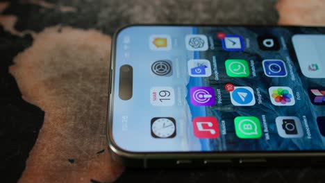 IPhone-15-Pro-Max-Liegt-Flach-Auf-Dem-Tisch,-Auf-Dem-Bildschirm-Sind-Symbole-Zu-Sehen