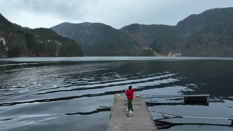 Tourist-taking-photograph-of-Norway-fjord-from-pier