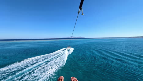 Punto-De-Vista-De-Planeo-Con-Paracaídas-Sobre-El-Hermoso-Mar,-Remolcado-Por-Barco-Mientras-Practica-Parasailing