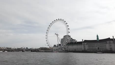 Gazing-at-the-London-Eye-from-Westminster-Pier-or-the-embankment,-known-as-the-Millennium-Wheel,-embodies-the-spirit-of-travel-and-exploration,-along-with-admiration-for-its-architectural-marvel