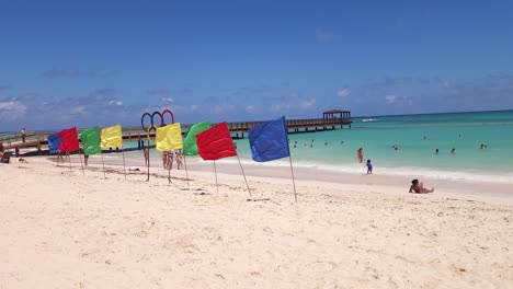 People-in-water-with-flags-waving-on-Blue-Beach-in-Punta-Cana,-Dominican-Republic