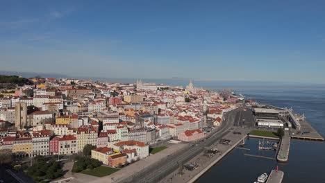 Drone-ascends-above-Tagus-River-promenade-to-establish-Lisbon-Portugal-at-midday