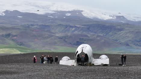 Drones-Flying-Above-and-Around-Abandoned-Airplane-and-Tourists-on-Coast-of-Iceland