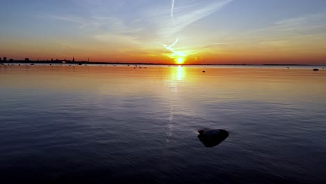 Peaceful-sunset-scene-over-a-Tallinn-Bay,-Baltic-sea,-with-a-rock-jutting-out-from-the-foreground-in-the-center-of-the-frame,-Tracking-right