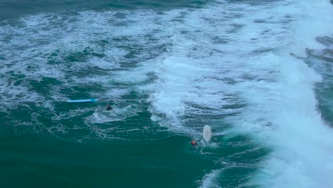 Drone-shot-of-surfers-playing-and-surfing-backwards-during-high-tide-in-Carlsbad-California