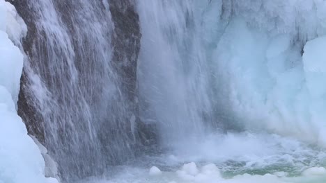 Rock-covered-in-ice-from-a-plunging-waterfall,-Helgufoss,-Southern-Iceland