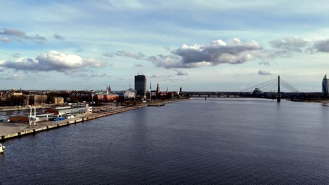 Rigaer-Stadtbild-Mit-Luftdrohne-Und-Skyline-Der-Stadt-In-Der-Ferne-An-Einem-Klaren,-Sonnigen-Tag-Und-Hafenanlegestelle-über-Dem-Meer