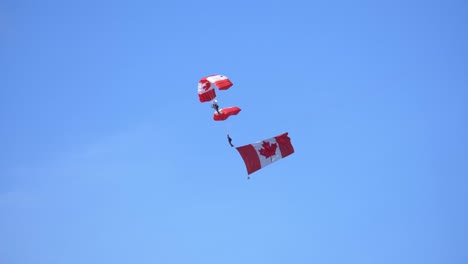 Fallschirmspringer-Team-Zeigt-Kanadische-Flagge-Bei-Airshow-Blauen-Himmelshintergrund