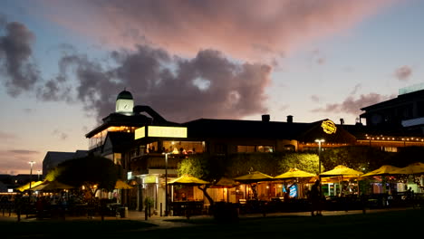 Luces-Cálidas-Y-Acogedoras-De-Los-Restaurantes-Hermanus-En-El-Paseo-Marítimo-Con-Cielo-Crepuscular