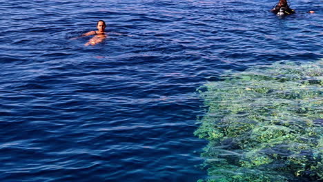 Female-tourist-floating-in-the-ocean-by-a-scuba-diver