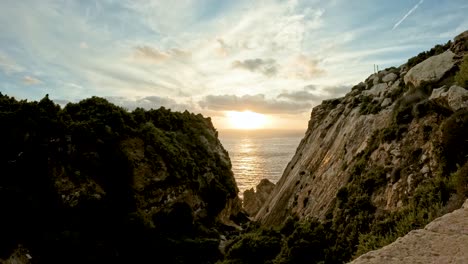 The-sun-sets-over-an-enclosed-bay,-cliffs-casting-shadows-in-this-captivating-time-lapse