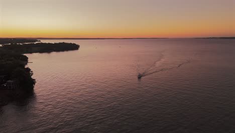 Cinematic-aerial-view-of-a-boat-sailing-the-Paraná-River-during-sunset