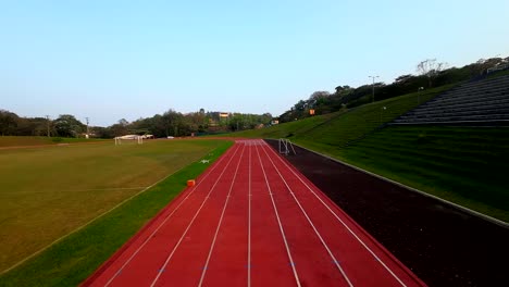 Dynamische-Ansicht-Einer-Drohne-Von-Der-Strecke-über-Einer-Tartanbahn-Für-Leichtathletik