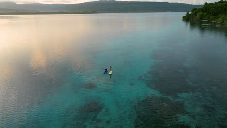 Vista-Aérea-De-Una-Pareja-En-Kayak-Y-Paddle-Board-En-La-Isla-De-Moso,-Vanuatu---Disparo-De-Un-Dron
