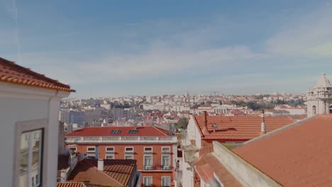 Aerial-dolly-rises-between-narrow-building-alleyway-to-reveal-scenic-historic-roofs-of-Lisbon-Portugal