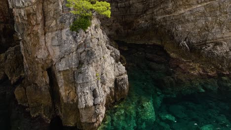 Kalamota-Island,-Adriatic-Sea,-Croatia---The-Untouched-Azure-Waters-Close-to-the-Steep-and-Rugged-Cliffs---Pan-Up-Shot