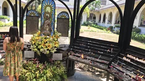 A-woman-lit-a-candle-and-pray-in-front-of-a-catholic-image