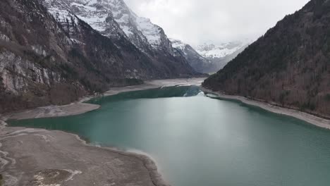 Vuelo-De-Drones-Sobre-Klöntalersee-En-Suiza---Altas-Montañas-Con-Nieve-En-El-Fondo