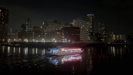 Barco-Navegando-Por-La-Noche-En-El-Río-Ookagawa-Ooka-Edificios-Del-Paisaje-Urbano-Japonés-Atmósfera-De-Viaje-Durante-La-Noche