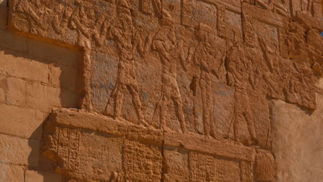 Egyptian-hieroglyphs-carved-red-wall-in-Ancient-Egypt,-Egyptian-language-in-oasis-North-Africa-desert
