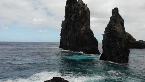 The-drone-captures-the-rugged-beauty-of-the-Ribeira-da-Janela-rocks,-showcasing-their-imposing-presence-amidst-the-natural-splendor-of-Madeira-Island