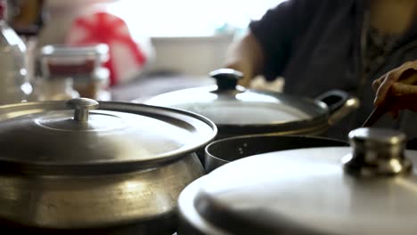 Cooking-pots-on-a-stove,-individuals-lifting-lids-amid-swirling-vapor,-embodying-the-essence-of-culinary-artistry-and-gastronomy