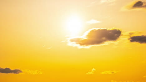 Timelapse-of-rolling-clouds-in-open-sky,-orange-glare-while-sun-paints-the-sky