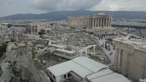 Drone-footage-over-Athens,-Greece,-showcasing-the-ancient-Acropolis,-tourists-exploring,-and-a-panoramic-view-of-Athens-from-the-Acropolis-hill