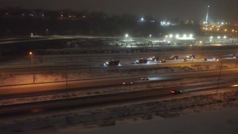 Wintry-night-view-of-busy-Montreal-highways-with-snow,-city-lights-in-distance,-elevated-angle