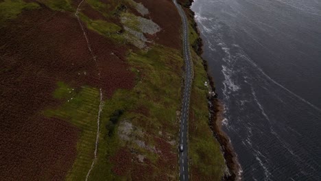 Drone-shot-of-a-long-road-following-the-shoreline-of-a-lake-or-loch-in-Scottish-highlands