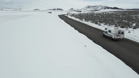 RV-Camper-Truck-Driving-In-Snowy-Winter-Landscape-In-Idaho---Aerial-Drone-Shot