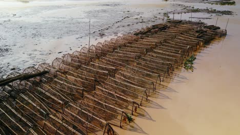 Fischfallen-Werden-Gelagert-Und-Warten-Auf-Die-Rückkehr-Der-Regenfälle-An-Der-Küste-Des-Tonle-Sap,-Asiens-Größtem-Binnensee.-Eine-Drohne-Fliegt-Darüber