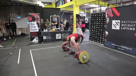 Male-athlete-failing-a-clean-and-jerk-wearing-a-red-and-black-singlet