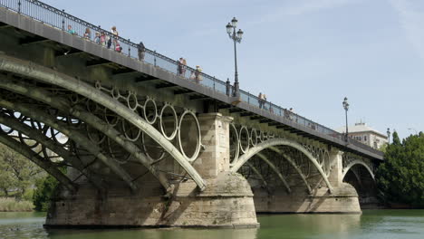 Menschen,-Die-Entlang-Der-Triana-Brücke-über-Den-Fluss-Guadalquivir-In-Sevilla,-Spanien-Spazieren