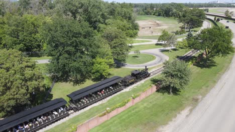 Alte-Dampflokomotive-Befördert-Touristen-Im-Historischen-Dorf-Auf-Der-Grünen-Wiese,-Luftaufnahme