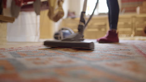 Housewife-stay-at-home-mom-hoovering-rug-in-living-room,-shallow-focus-low-angle