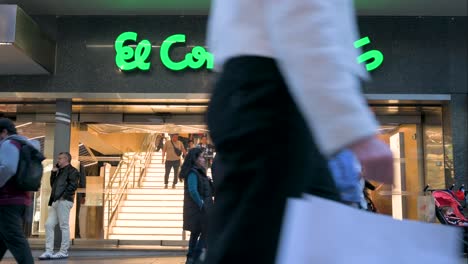 Los-Peatones-Y-Los-Compradores-Se-Ven-En-La-Entrada-De-Los-Grandes-Almacenes-Más-Grandes-De-España,-El-Corte-Inglés,-Durante-La-Noche.