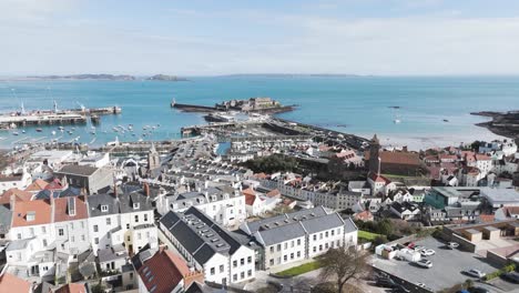 Flug-Hoch-über-Den-Dächern-Von-St.-Peter-Port-Aufs-Meer-Hinaus-über-Den-Hafen,-Albert-Marina,-Fischereiflotte,-Modellyacht-Teich-Und-Castle-Cornet-Mit-Blick-Auf-Die-Inseln-An-Einem-Sonnigen-Tag