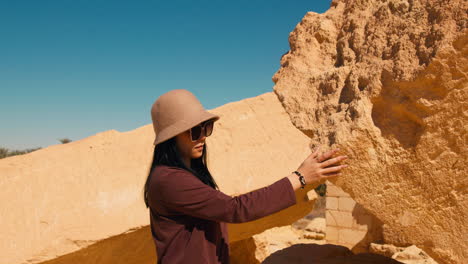 Asiatic-woman-tourist-visiting-North-Africa-desert-touching-ancient-ruins-in-Siwa-oasis-Qattara-Depression-and-the-Great-Sand-Sea-in-the-Western-Desert-in-Egypt
