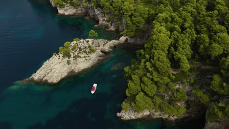 Kalamota-Island,-Adriatic-Sea,-Croatia---A-Sailboat-Gliding-on-the-Pristine-Blue-Waters-Close-to-the-Rugged-and-Steep-Cliffs---Aerial-Drone-Shot