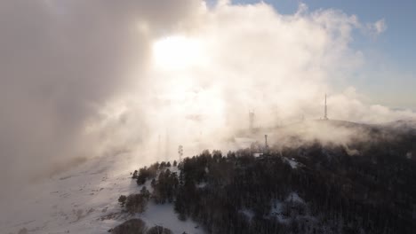 Heavy-cloud-inversion-hovering-above-snowy-mountain-and-shrouding-sun