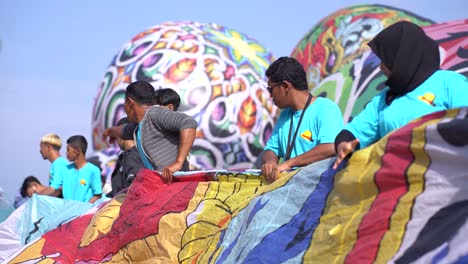 Participants-roll-up-a-hot-air-balloon-that-has-finished-flying-as-part-of-the-hot-air-balloon-festival-in-the-twin-village,-Wonosobo