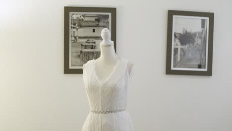 A-white-lace-wedding-dress-is-displayed-on-a-mannequin-in-a-hotel-room