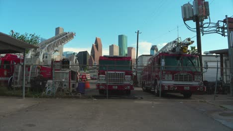 Establishing-shot-of-yard-full-of-disabled-fire-trucks-with-downtown-Houston-in-the-background