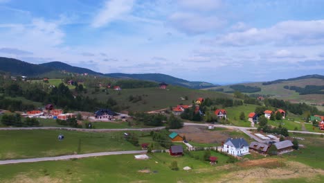 Vista-Aérea,-Paisaje-De-La-Montaña-Zlatibor,-Serbia,-Telecabina-De-Oro-Sobre-El-Pueblo-Y-Campos-Verdes