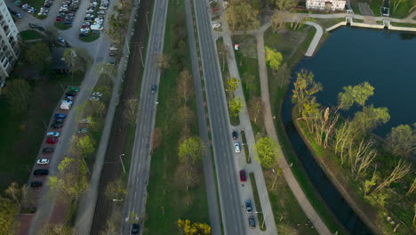 Drone-top-down-of-road-in-City-beside-lake-at-sunset-time
