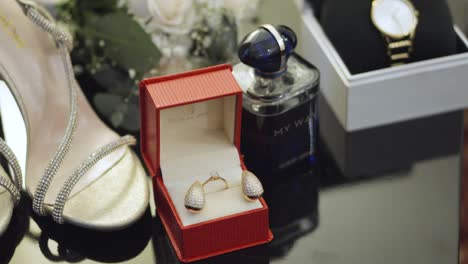 A-red-box-with-earrings-and-a-diamond-ring-inside-and-wedding-accessories-around