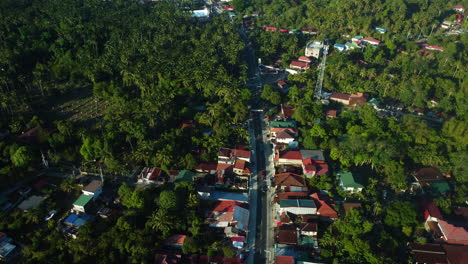 AERIAL:-Traffic-on-a-road-in-middle-of-rural-homes,-in-sunny-Luzon,-Philippines